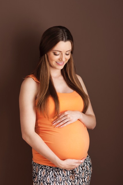 Lovely pregnant woman embracing abdomen